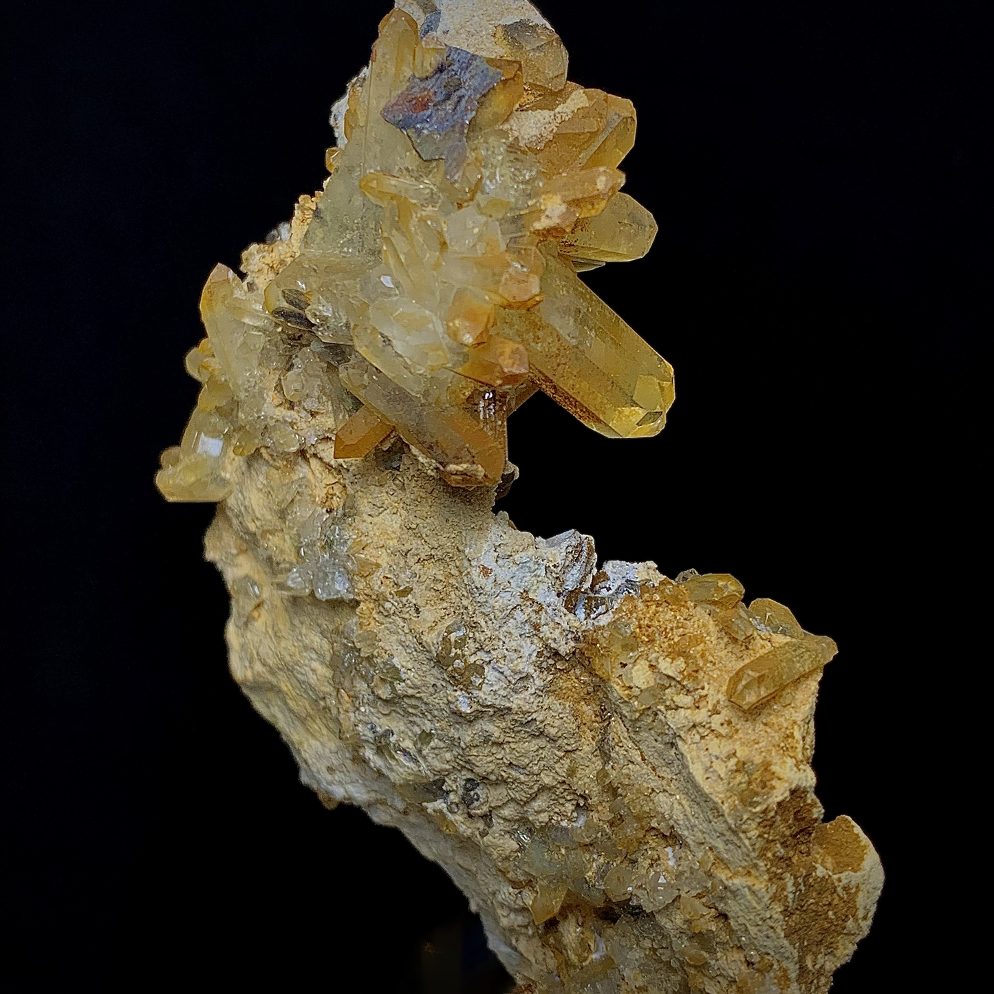 Close-up of a mineral specimen with yellow and beige crystals on a black background