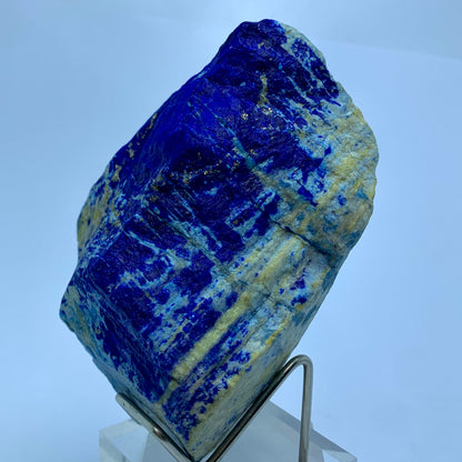 Blue mineral specimen on a stand against a light blue background