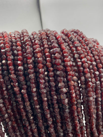 Multiple strands of faceted red beads, likely garnet, draped vertically to show off their texture and color.